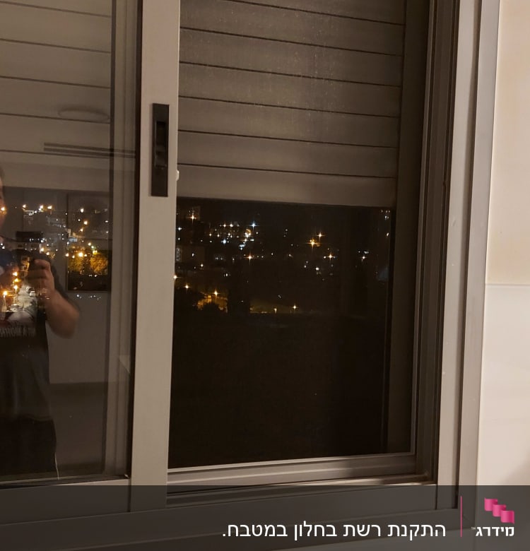 חלון אלומיניום עם תריסים סגורים בלילה